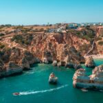 Wind-swept Atlantic cliffs on the Algarve west coast in April, with layered waves and rugged coastal headlands under shifting spring light