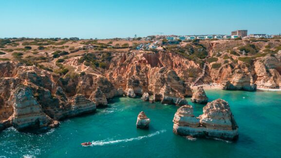 Wind-swept Atlantic cliffs on the Algarve west coast in April, with layered waves and rugged coastal headlands under shifting spring light